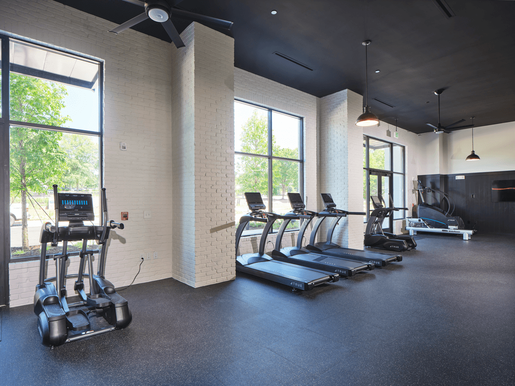 A gym with treadmills, elliptical machines, and a weight rack.