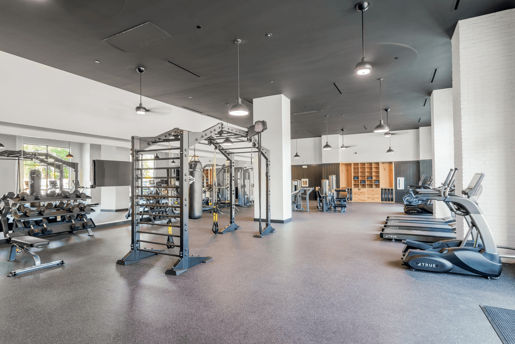 A spacious gym with a variety of equipment including treadmills, elliptical machines, and weight machines.