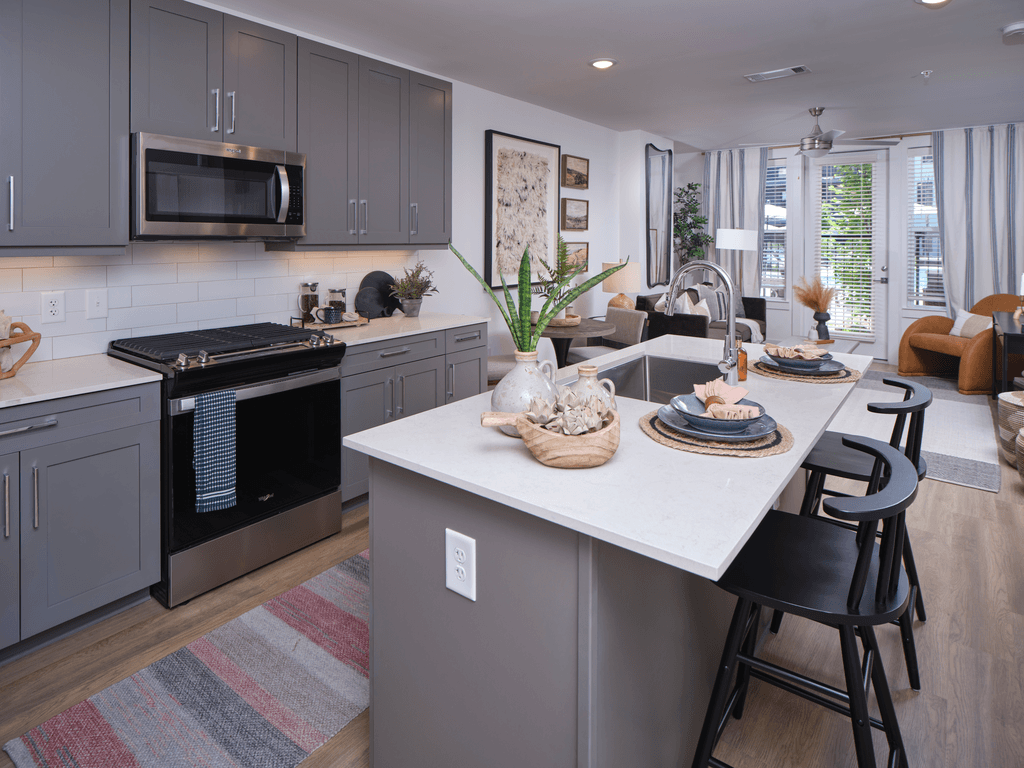 A kitchen with a white island and black chairs.