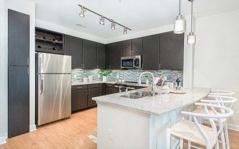 a kitchen with a large island and a stainless steel refrigerator