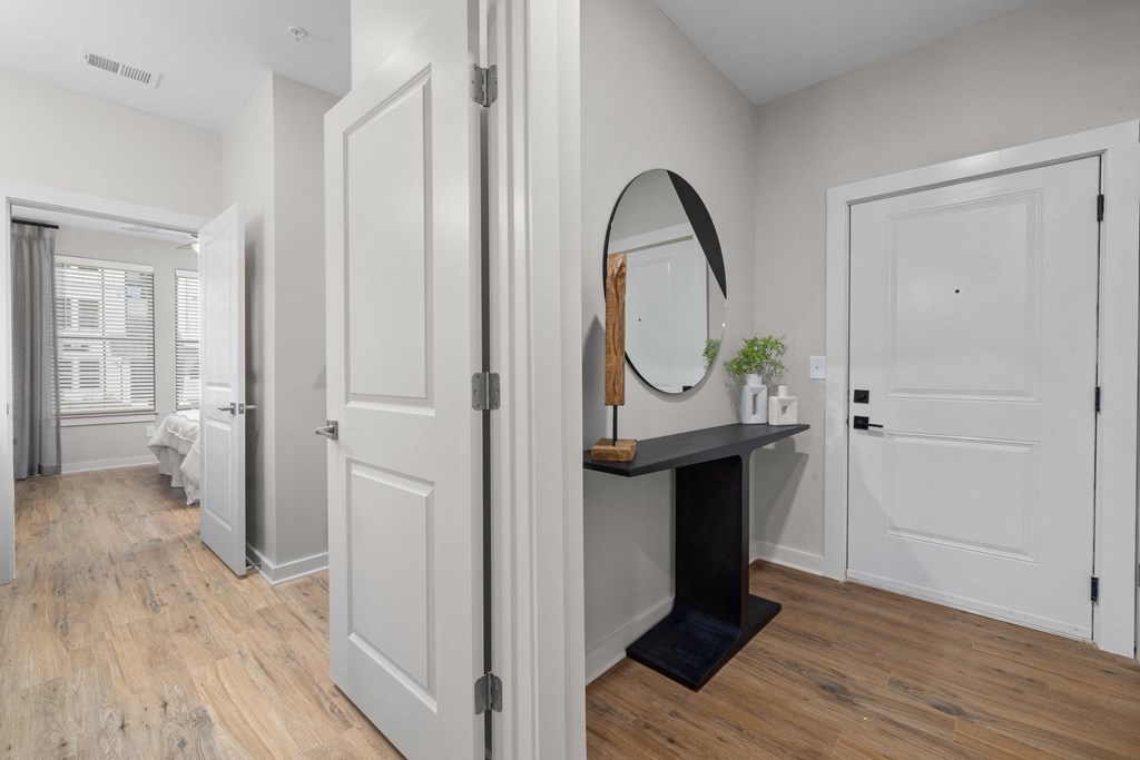a living room with white doors and a mirror and a hallway to a bedroom