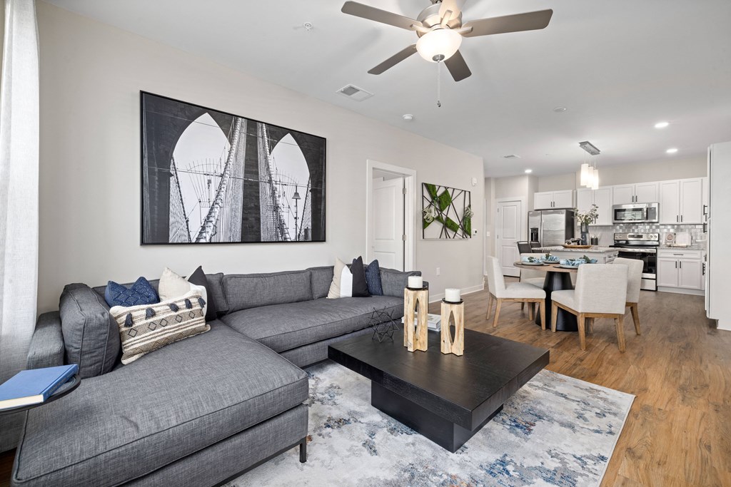 a living room with a gray couch and a ceiling fan