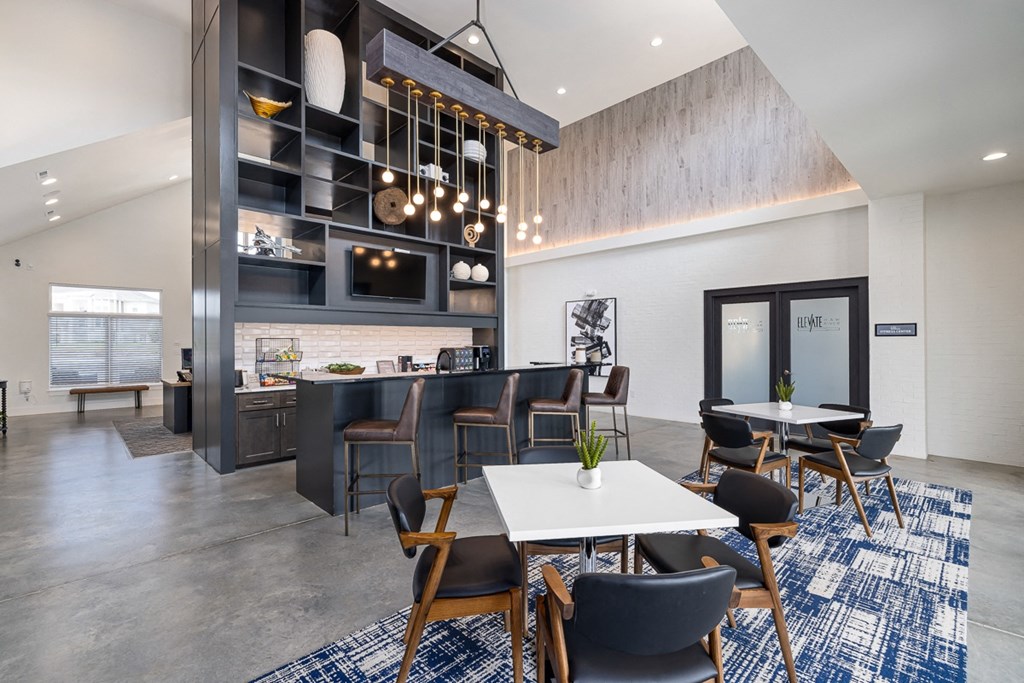 a communal area with tables and chairs and a kitchen area