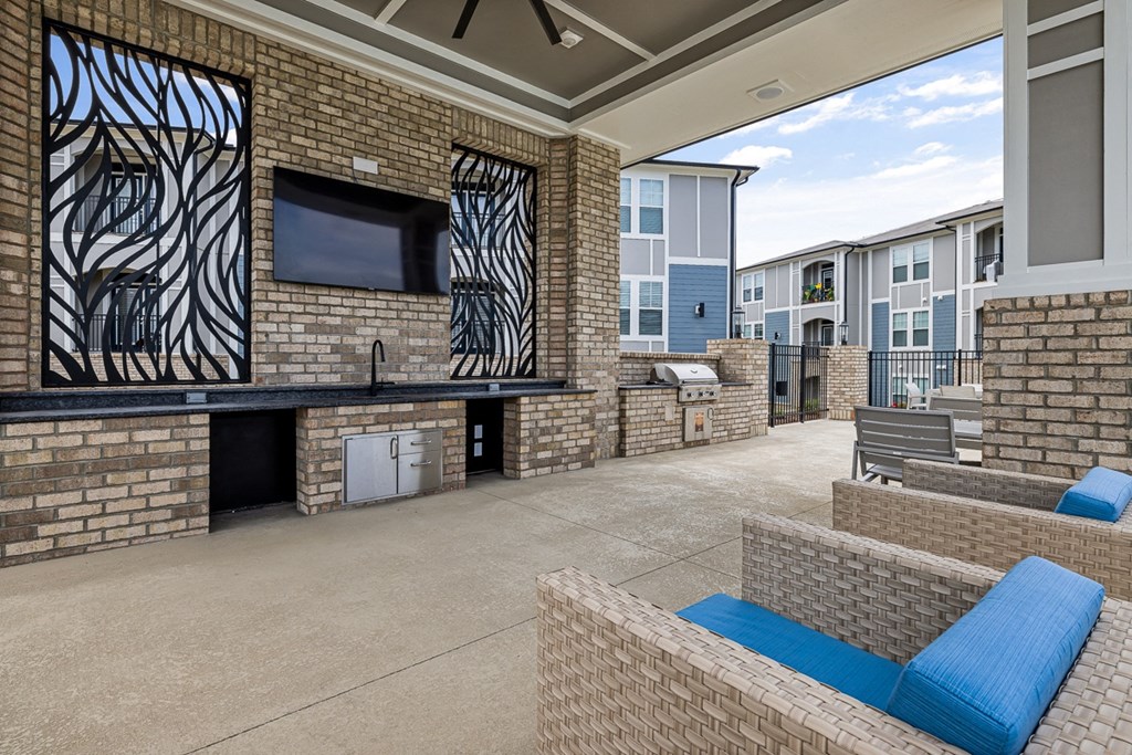 exterior poolside patio with seating, a tv and grills