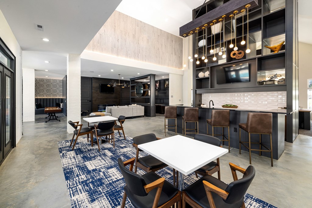 a communal area with tables and chairs and a kitchen and living room