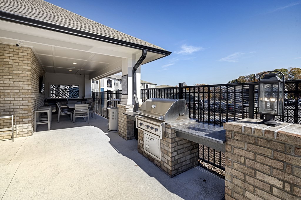 a covered patio with a barbecue grill and a table and chairs