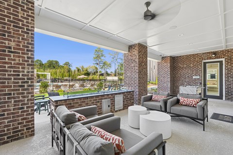 A patio with a grey couch and a white table.