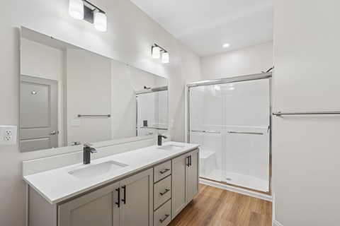 A bathroom with a sink, mirror, and shower.