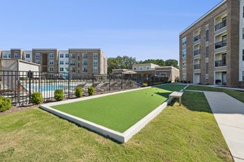 A grassy area in front of apartment buildings with a pool.
