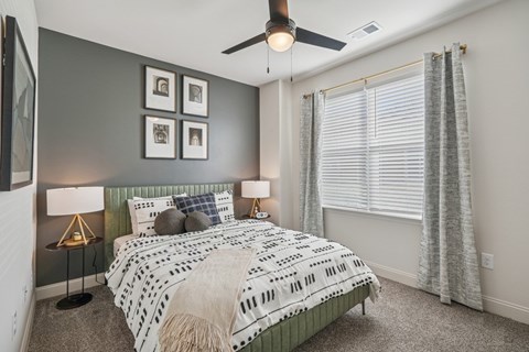 A bedroom with a bed, two lamps, and a ceiling fan.