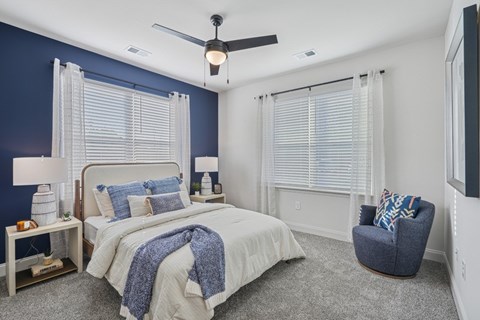 A bedroom with a bed, chair, and ceiling fan.