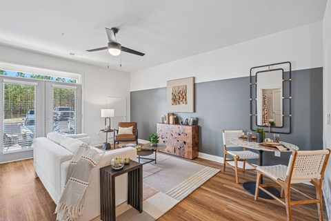 A living room with a white couch, a wooden coffee table, and a dining table set up.