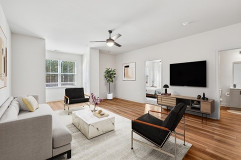 A living room with a grey couch, a white coffee table, a black chair, and a TV.