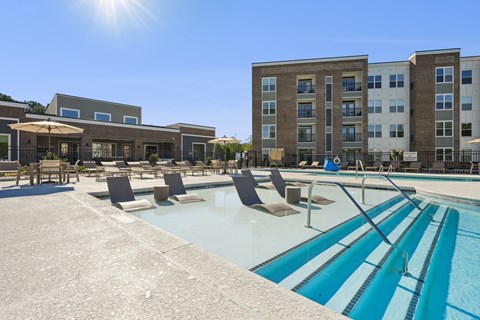 A sunny day at the pool with chairs and umbrellas.