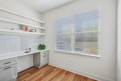 A den with a window and a plant on the counter.