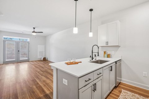 A kitchen with a white countertop and wooden floors.
