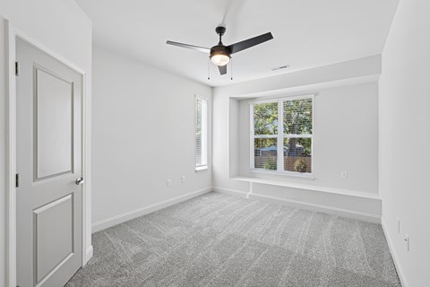 A room with a ceiling fan and a window with blinds.
