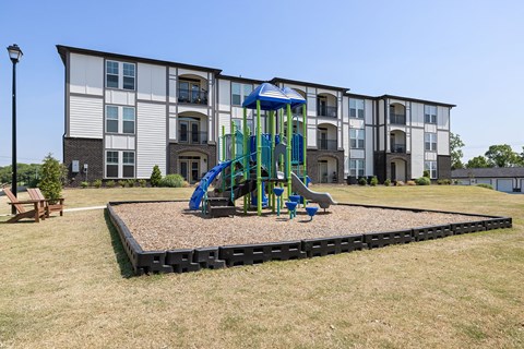 A playground with a blue slide in front of a building.