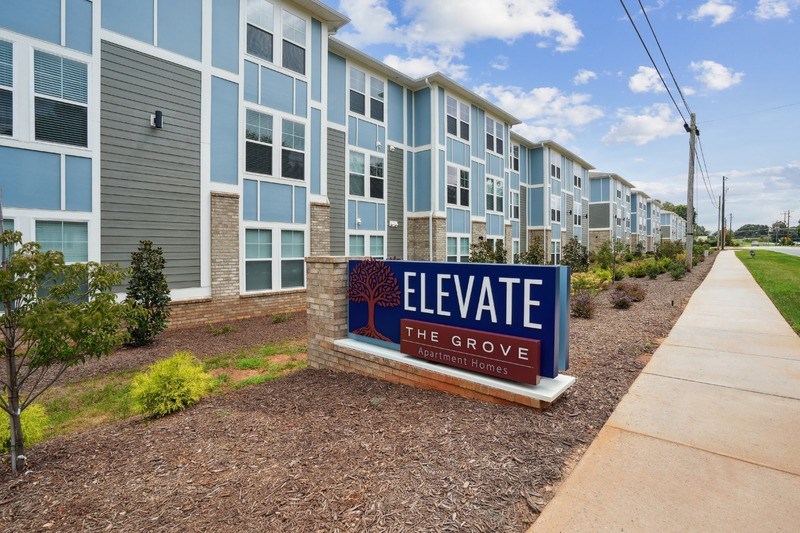A sign in front of apartment buildings that says Elevate.