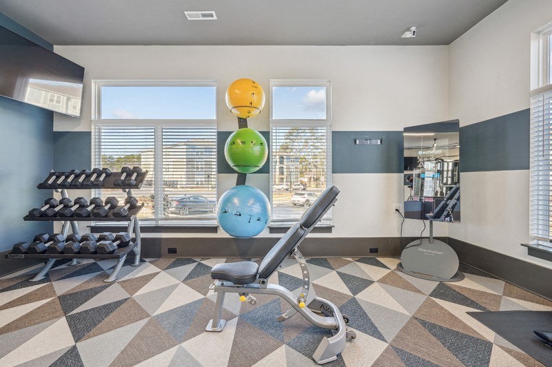 A gym with a variety of equipment including a rowing machine, dumbbells, and a bench press.
