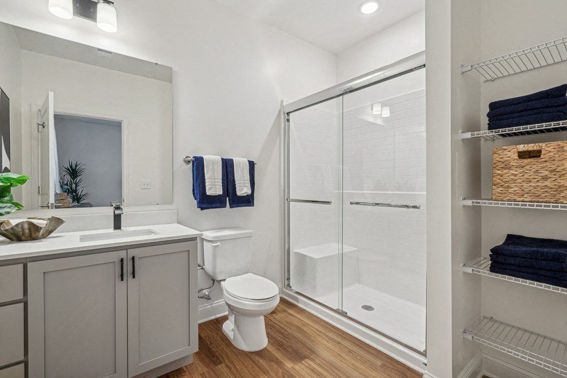 A bathroom with a toilet, sink, and a glass shower door.