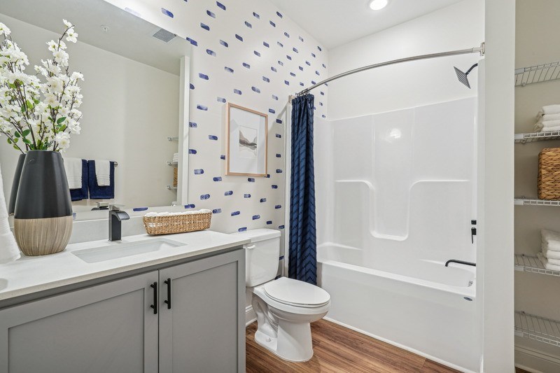 A white toilet sits in a bathroom with a blue and white wallpaper.