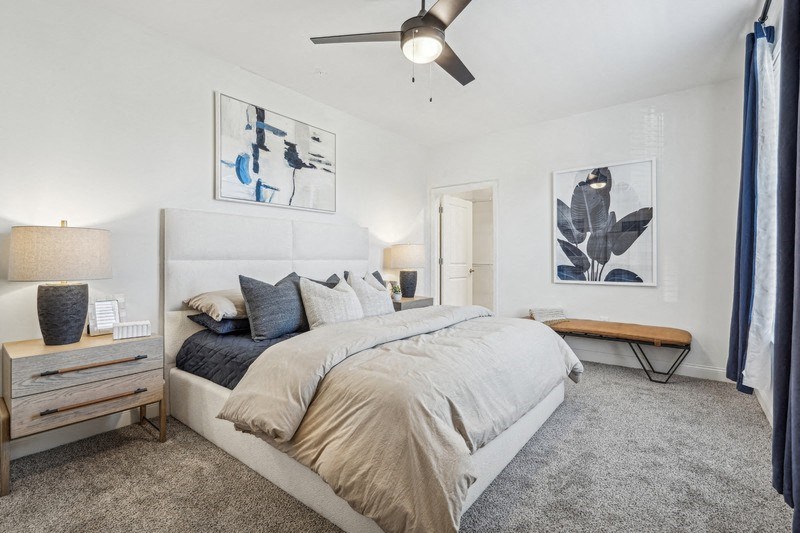 A bedroom with a large bed and a ceiling fan.