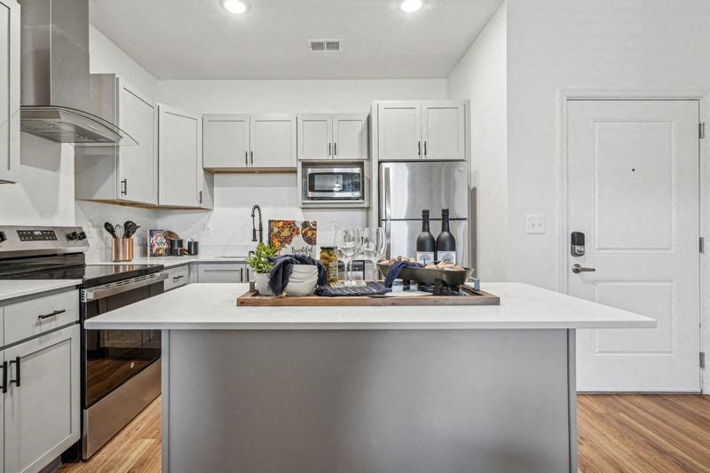 A modern kitchen with a white island and stainless steel appliances.