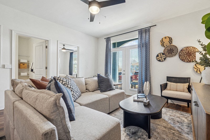 A living room with a grey couch, a black coffee table, and a ceiling fan.