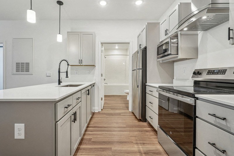 A modern kitchen with stainless steel appliances and wooden floors.