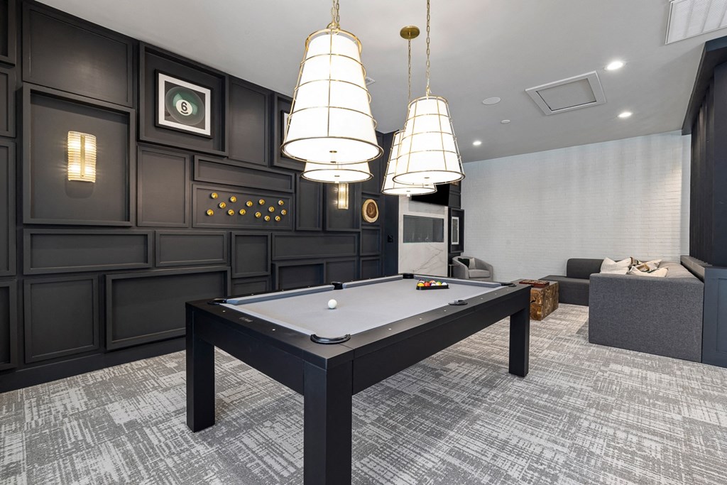 a billiards table in a game room with three lamps