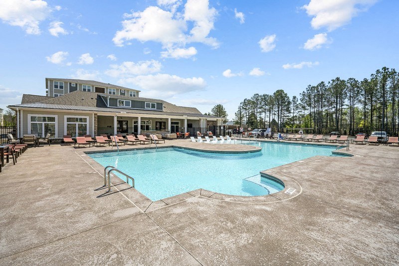 a resort style pool with lounge chairs and a building in the background