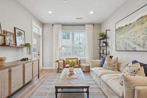 A living room with a large couch, a coffee table, and a painting on the wall.