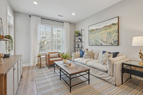 A living room with a sofa, a coffee table, and a painting on the wall.