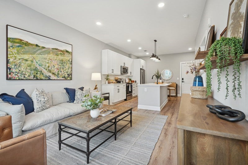 A living room with a white couch and a painting on the wall.