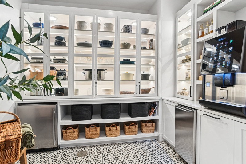 a kitchen with white cabinets and appliances and a glass door refrigerator