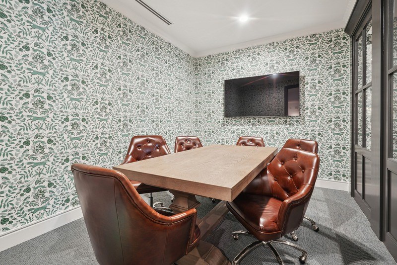 A conference room with a wooden table and brown chairs.