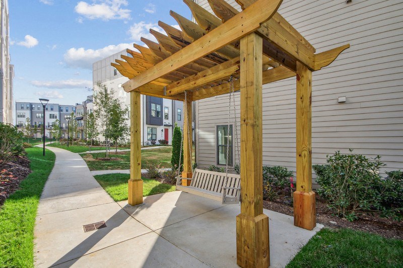a wooden pergola on a sidewalk next to a building