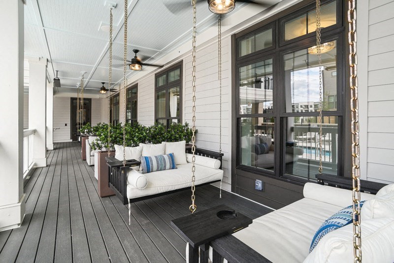 the porch of a house with swings and plants