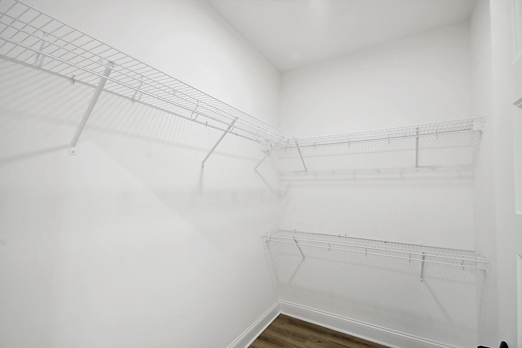 an empty closet with white walls and a wood floor