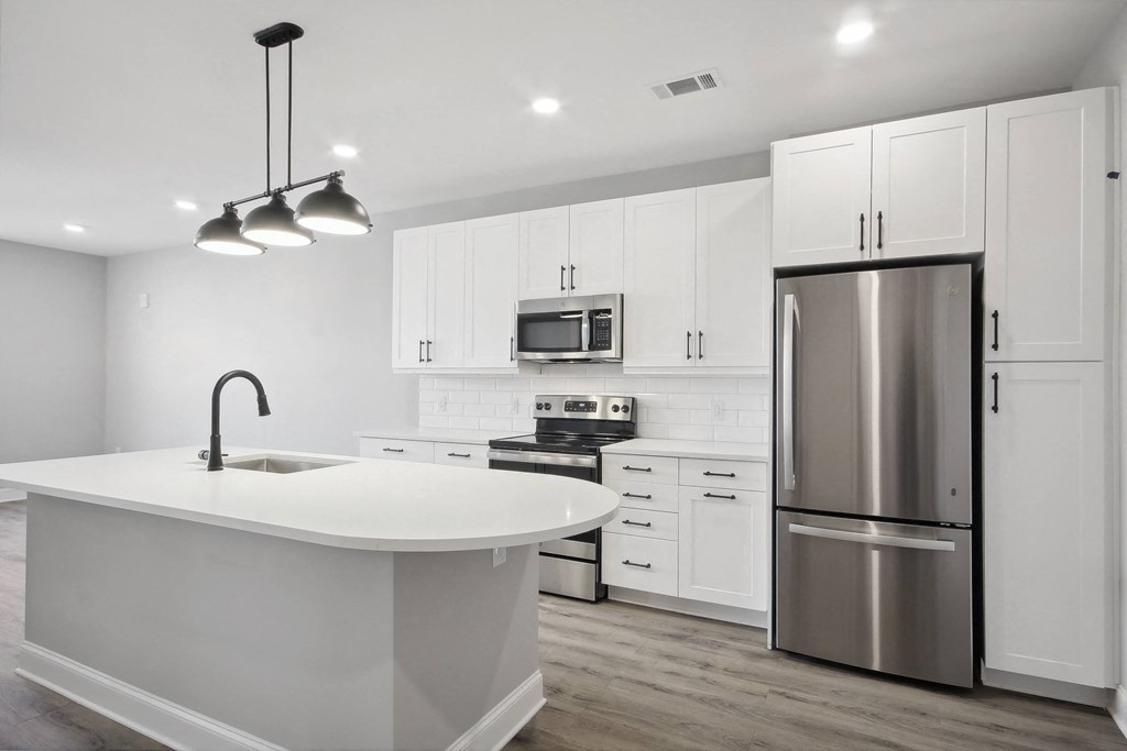 a white kitchen with stainless steel appliances and a white counter top