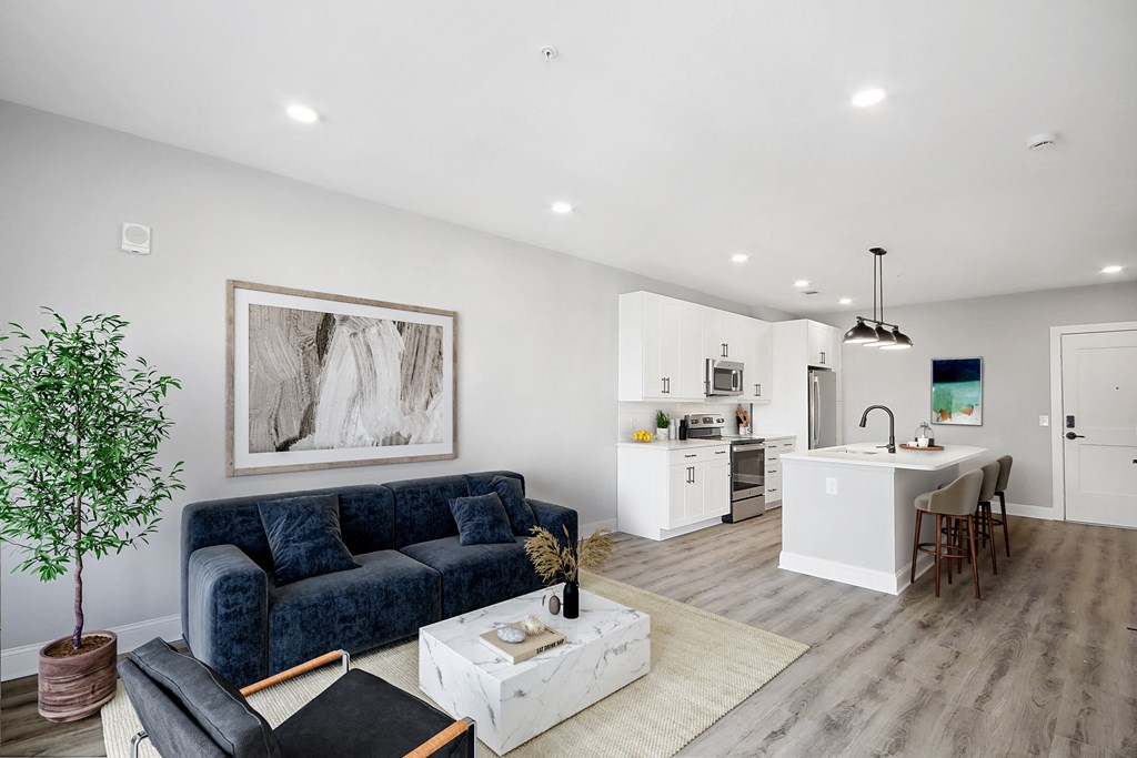 a living room with a couch and a table in front of a kitchen