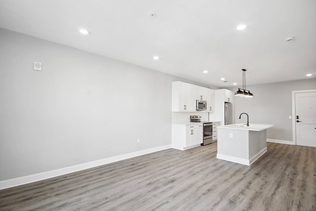 a living room and kitchen with white walls and wood floors