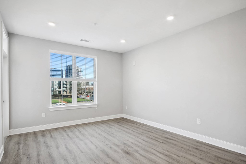 an empty bedroom with white walls and a window