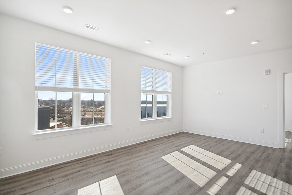 an empty living room with three windows and a wood floor