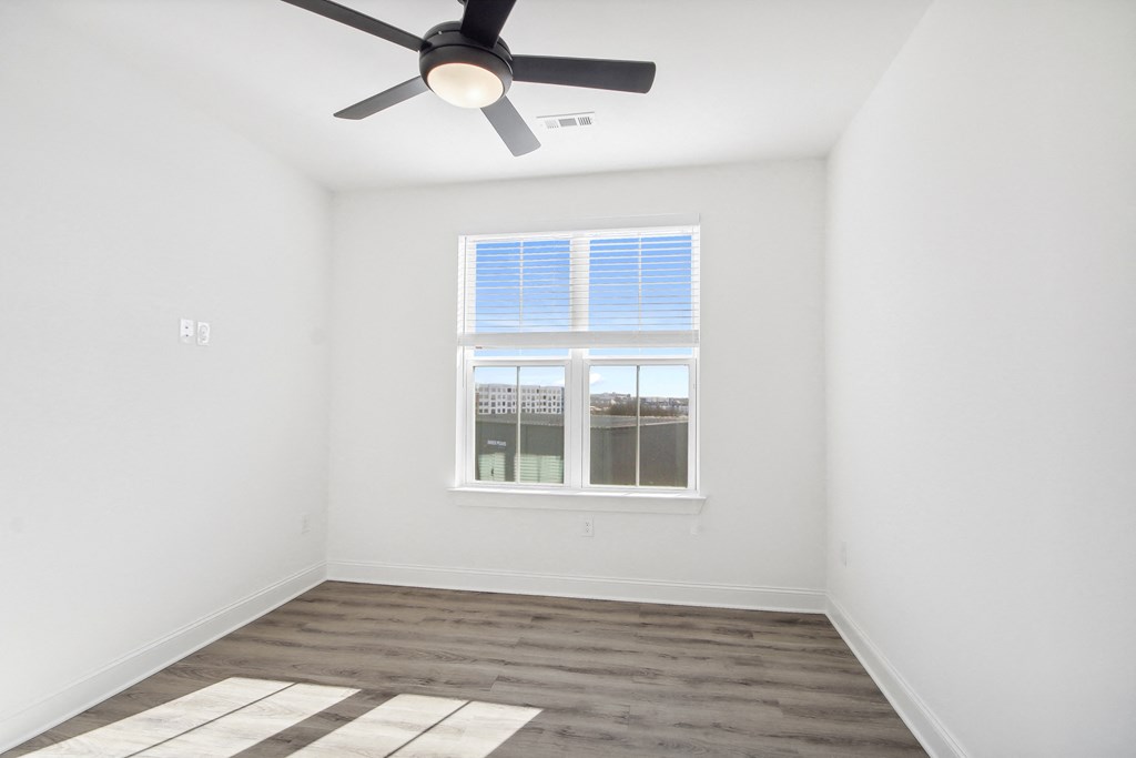 an empty room with a ceiling fan and a window