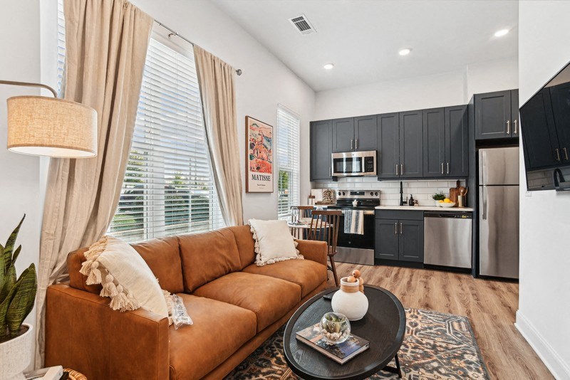 a living room with a couch and a table in front of a kitchen