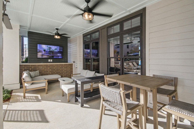 a covered patio with a table and chairs and a tv