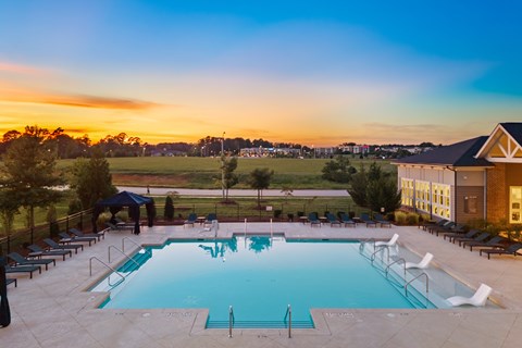 A large outdoor swimming pool surrounded by lounge chairs and umbrellas.