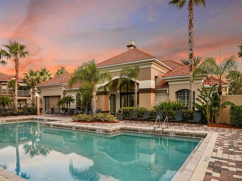 Resort-style swimming pool and clubhouse at sunset
